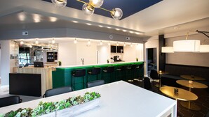 A modern restaurant with a bar area, seating, and a ceiling light fixture. - Hotel Denim (Greensboro)