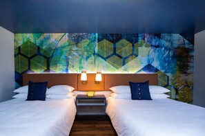 A hotel room with two beds, a nightstand with a telephone, and a wall with a geometric pattern.