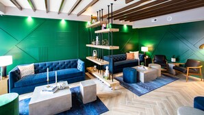 A modern living room with a blue sofa, a coffee table, and a bookshelf. - Hotel Denim (Greensboro)