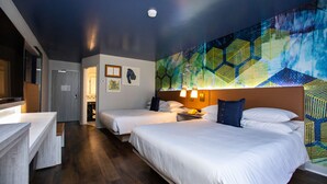 A hotel room with two beds, a desk, and a large abstract painting on the wall. - Hotel Denim (Greensboro)