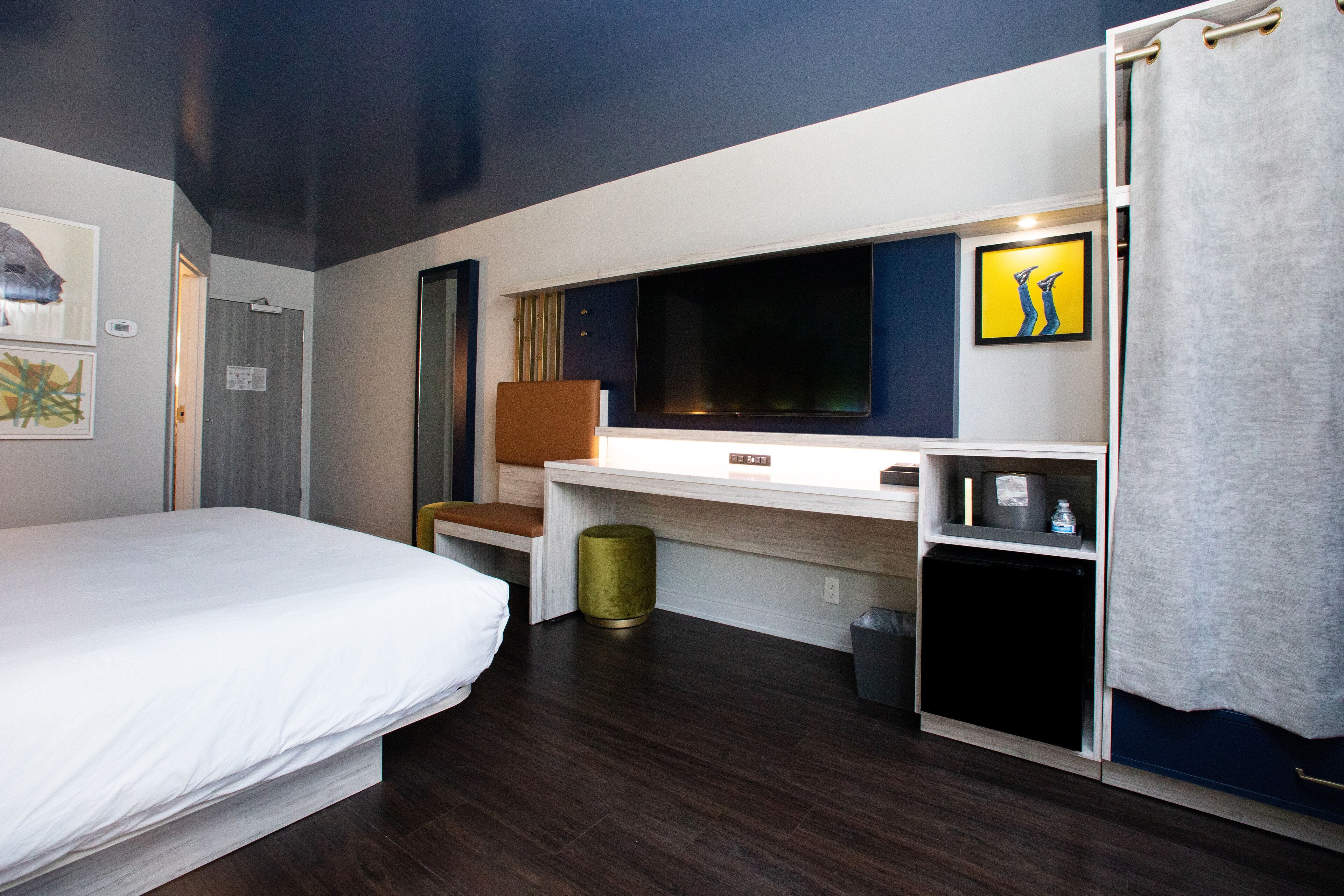 Una camera d'albergo con un letto, una scrivania con un computer, una televisione e un angolo cottura.