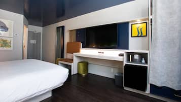 Una camera d'albergo con un letto, una scrivania con un computer, una televisione e un angolo cottura.