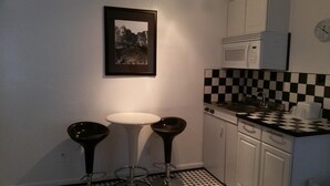 A compact kitchen with a white sink, a microwave, and a checkered backsplash. There is a framed picture on the wall above the sink. - Rocket Motel (Custer)