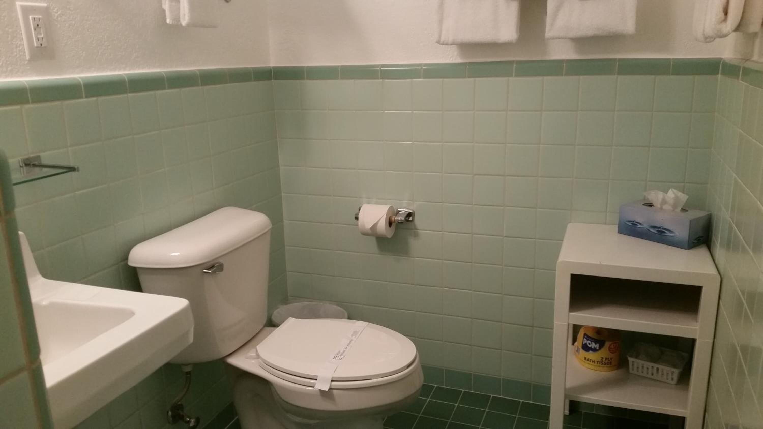 Een kleine badkamer met toilet, wastafel en een plank met toiletartikelen.