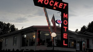 A motel sign with neon lights, an American flag, and a neon sign for AAA. - Rocket Motel (Custer)