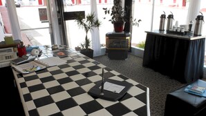 A checkered floor, a desk with a calculator, a potted plant, a fireplace, and a view of the outside. - Rocket Motel (Custer)