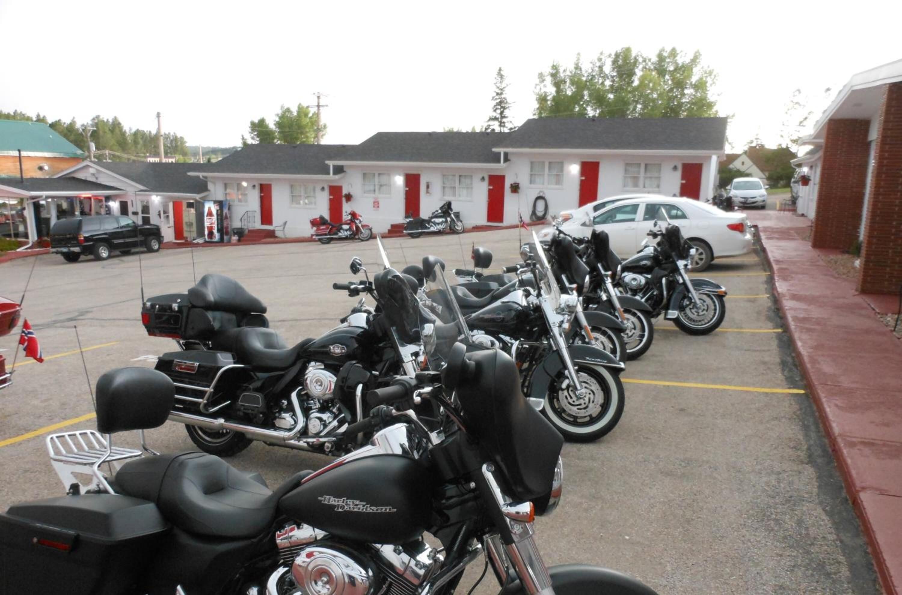 Varias motocicletas estacionadas en un estacionamiento, con un motel al fondo.