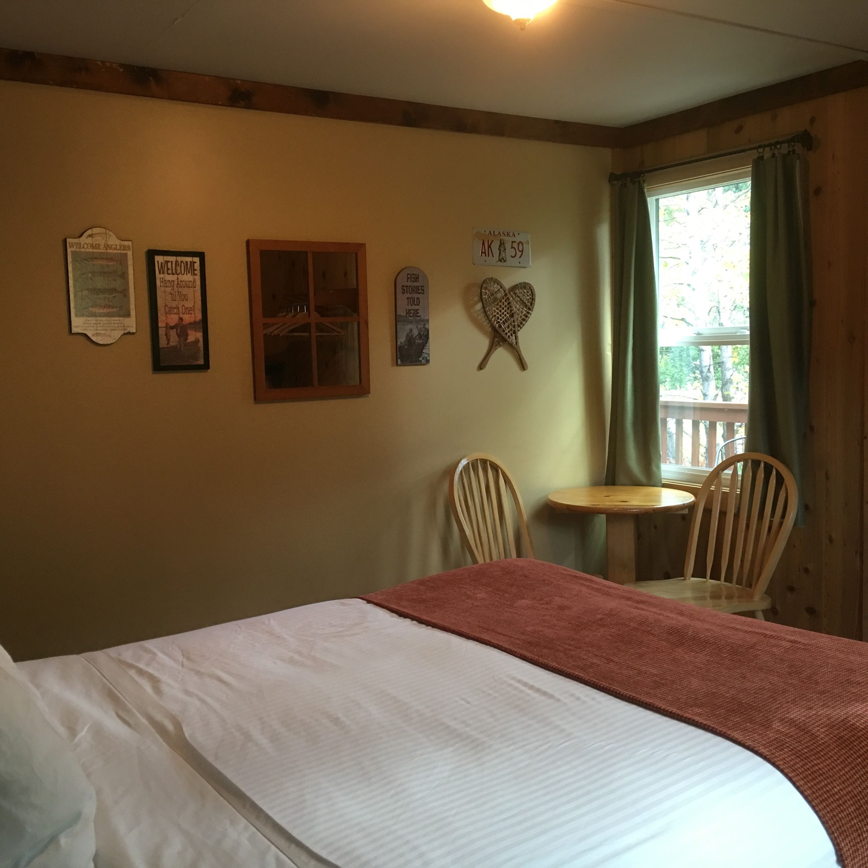 A room with a bed, two chairs, a small table, and a window with curtains.