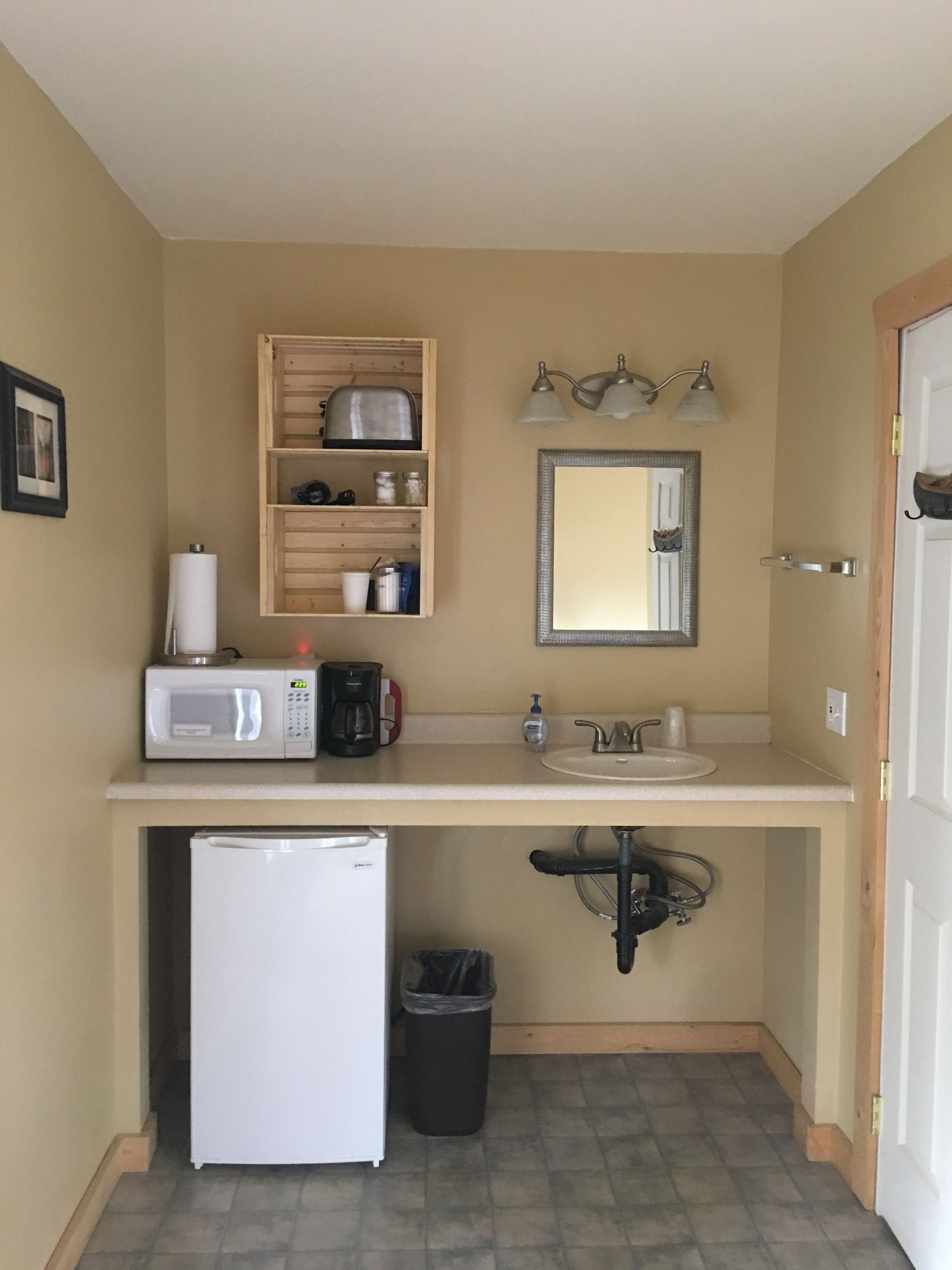 A compact kitchenette with a microwave, coffee maker, and a small refrigerator.