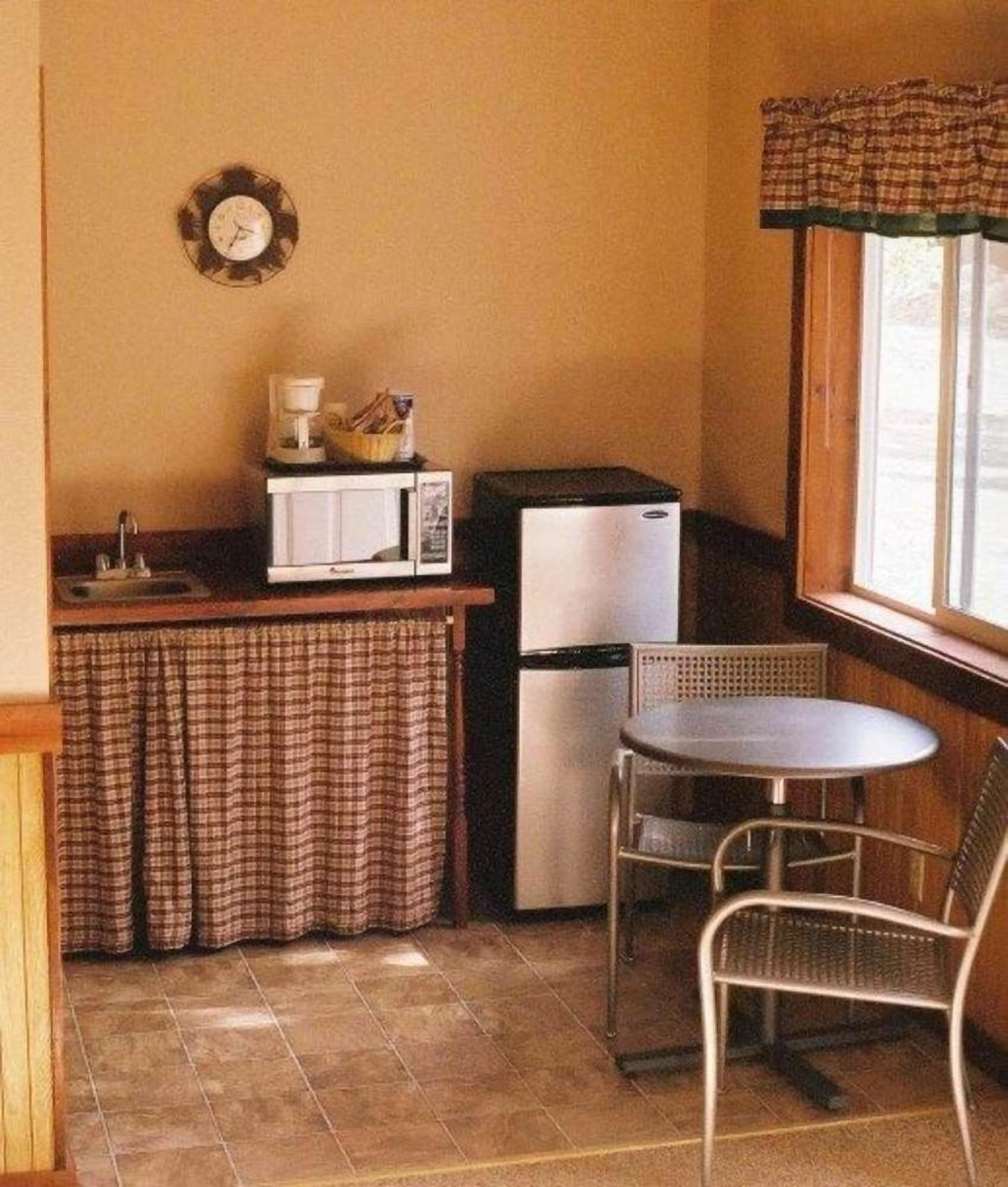 A compact kitchen with a microwave, refrigerator, and a small dining table with chairs.