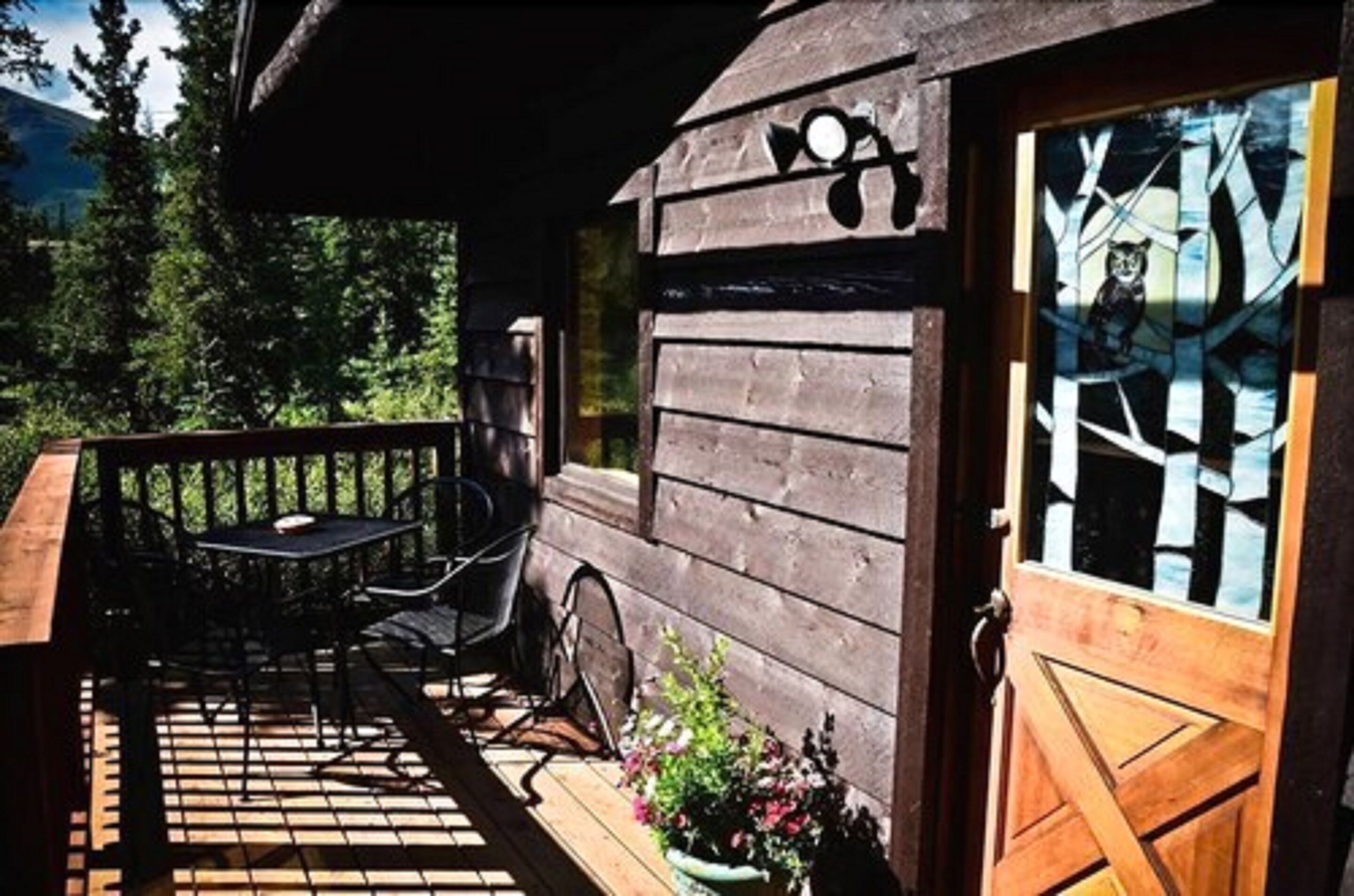 A wooden cabin with a deck, a table, and chairs.