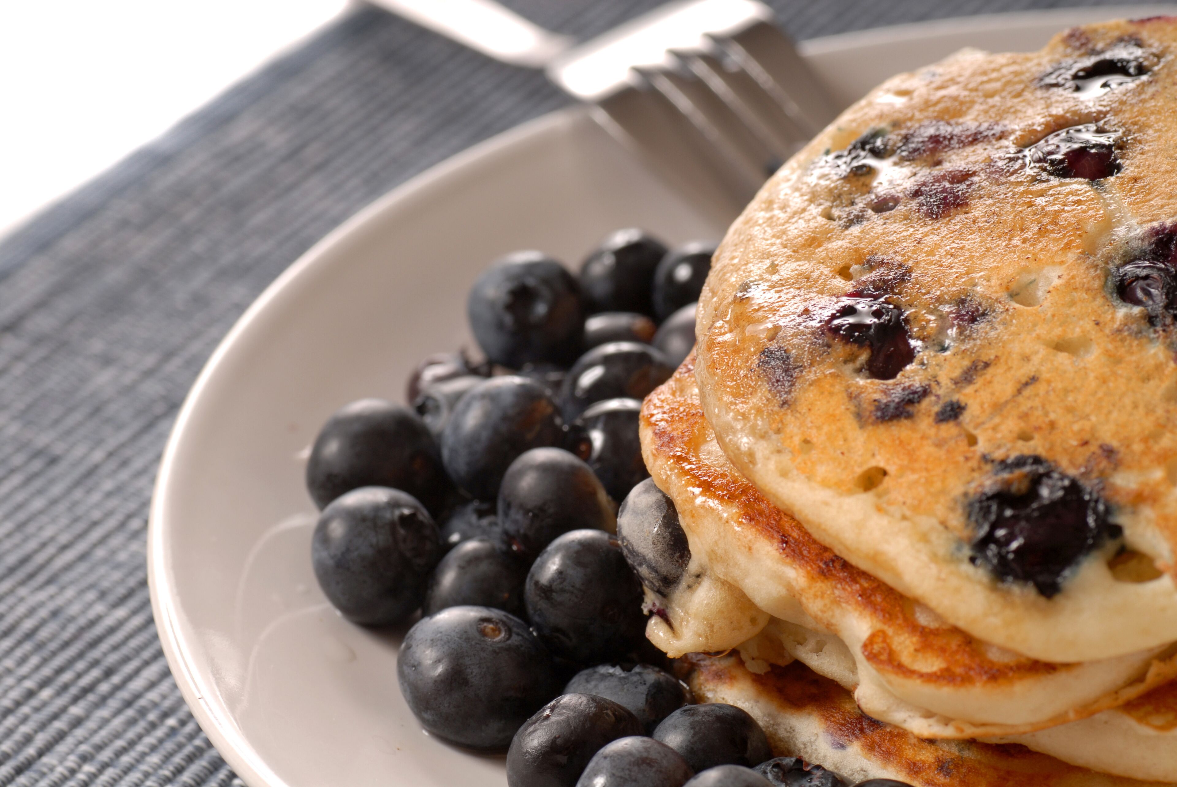 A plate of pancakes with blueberries on a table.