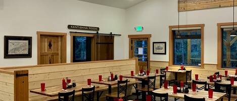 A restaurant with wooden tables and chairs, red cups, and a ceiling fan.