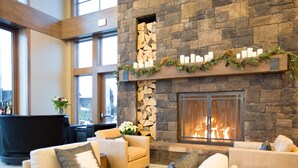 A modern living room with a stone fireplace, sofas, and a bar area. - Tetherow Resort (Bend)