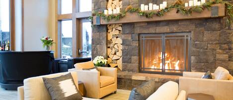 A modern living room with a stone fireplace, sofas, and a bar area.