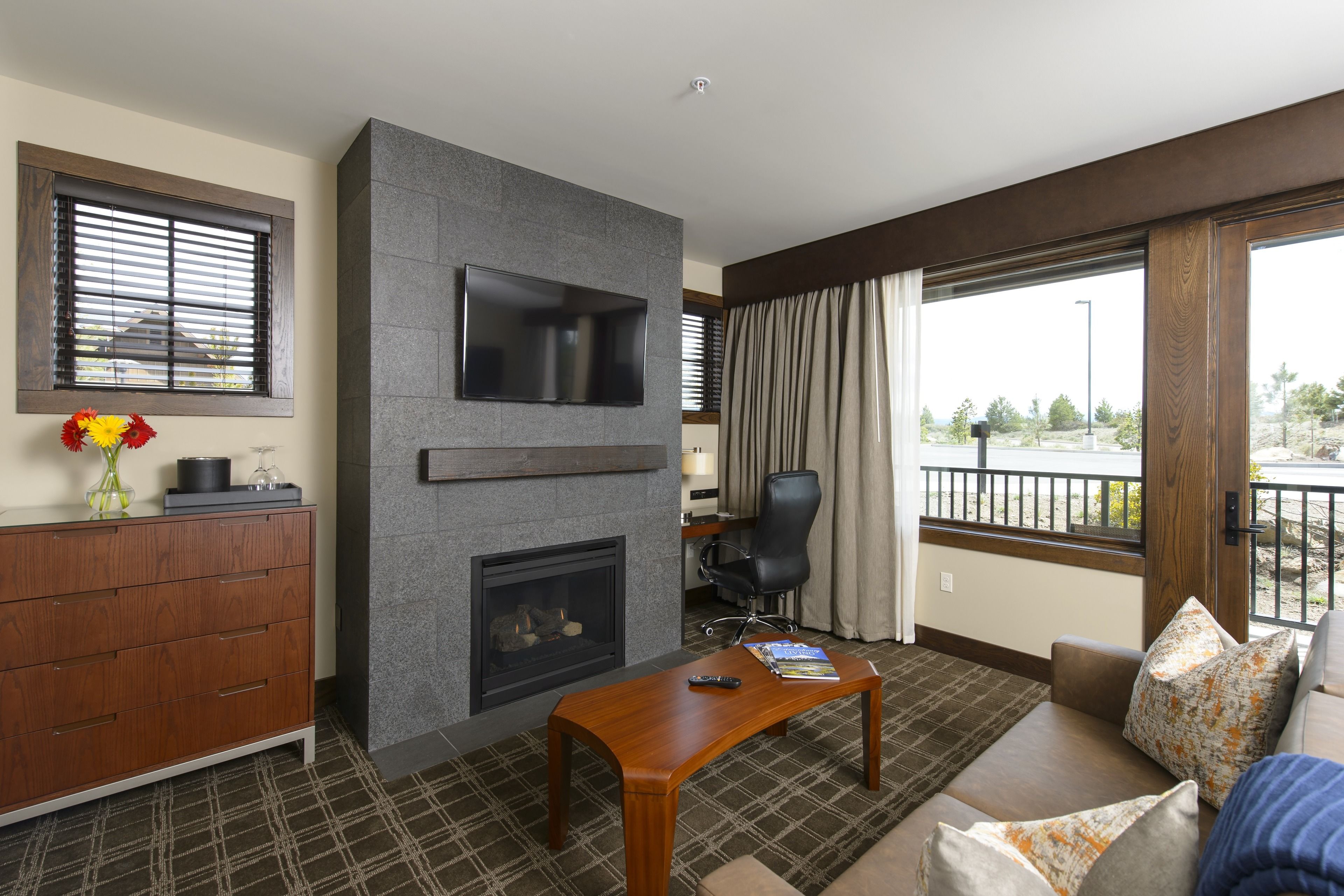 A modern living room with a fireplace, a flat-screen TV, a sofa, and a dining table.