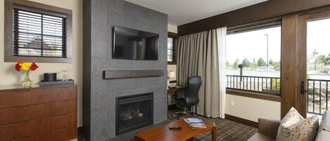 A modern living room with a fireplace, a flat-screen TV, a sofa, and a dining table.