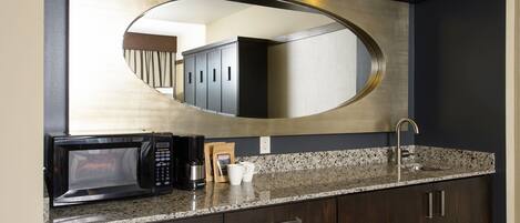 A kitchen with a microwave, coffee maker, and a sink.