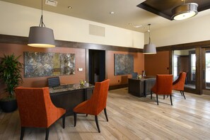 A modern reception area with a wooden floor, orange upholstered chairs, and contemporary artwork on the walls.