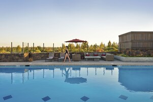 En swimmingpool med liggestole og en rød parasol.