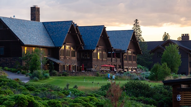 A large lodge with a steeply pitched roof, multiple chimneys, and a well-maintained lawn. - Tetherow Resort (Bend)