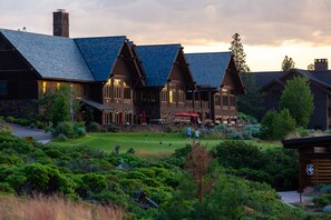 A large lodge with a steeply pitched roof, multiple chimneys, and a well-maintained lawn.