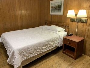 A neatly made bed with white bedding, a wooden nightstand with a phone, and wall-mounted lamps. - Lincoln Lodge (Urbana)