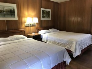 A hotel room with two beds, wooden paneling, and two wall-mounted lamps. - Lincoln Lodge (Urbana)