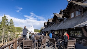 Il s’agit d’un bâtiment en bois au style rustique, doté d’une terrasse avec des chaises et des tables en bois.