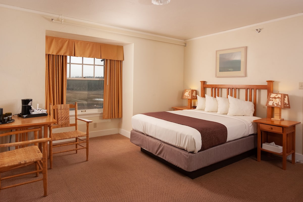 Une chambre d’hôtel comprenant un lit, des tables de chevet, un bureau et une chaise.