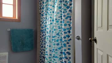 Un baño con cortina de ducha, una toalla, una ventana y una puerta.