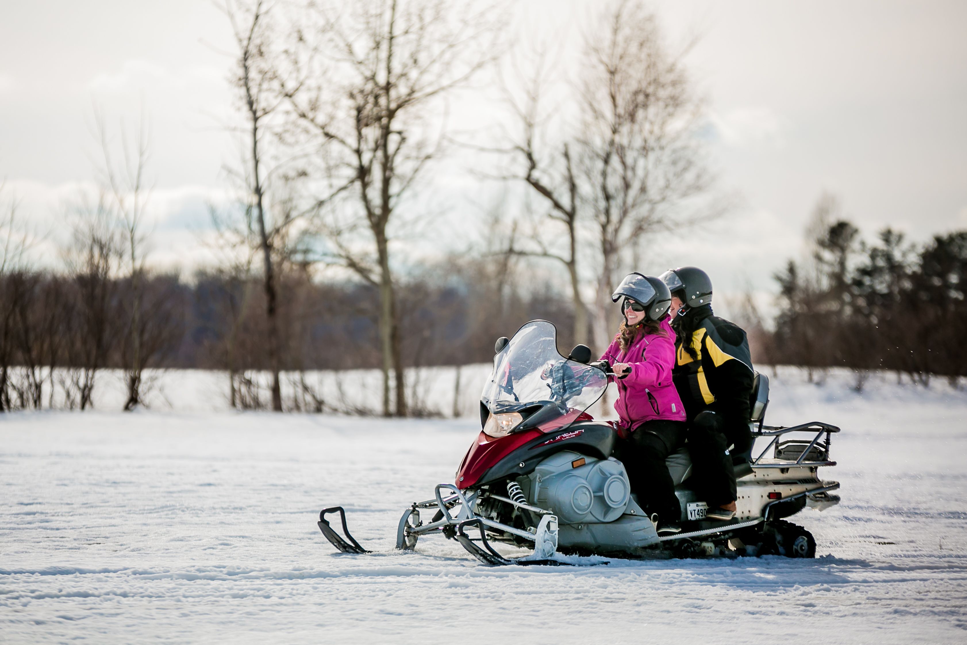 A snowmobile with two passengers on a snowy landscape.