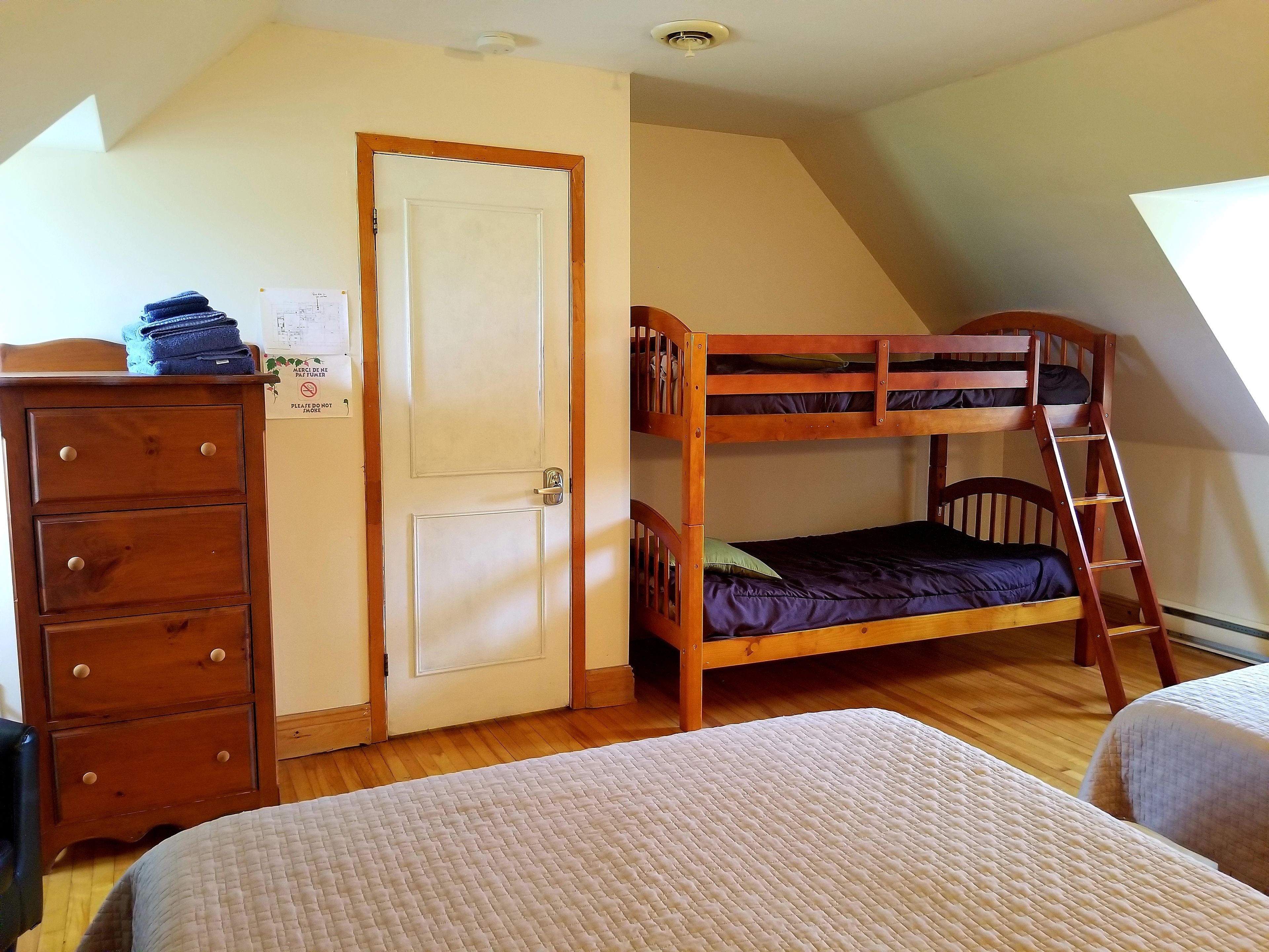 A room with a bunk bed, a dresser, and a door with a notice.