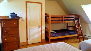 A room with a bunk bed, a dresser, and a door with a notice.