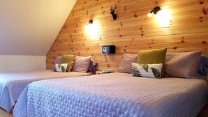 Un dormitorio acogedor con dos camas, paneles de madera en el techo y un termostato fijado a la pared.