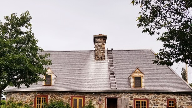 Un edificio de piedra con techo a dos aguas, una chimenea y una puerta de madera.