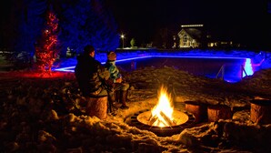 A snow-covered outdoor area with a fire pit and a Christmas tree. - Old Faithful Snow Lodge & Cabins - Inside the Park (Yellowstone National Park)