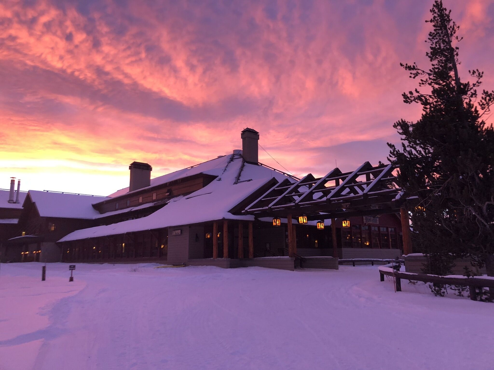 A lodge with a snow-covered roof and a wooden structure with a covered porch.