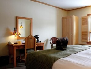 Une chambre d’hôtel comprenant un lit, un bureau, une chaise, un miroir et une armoire.