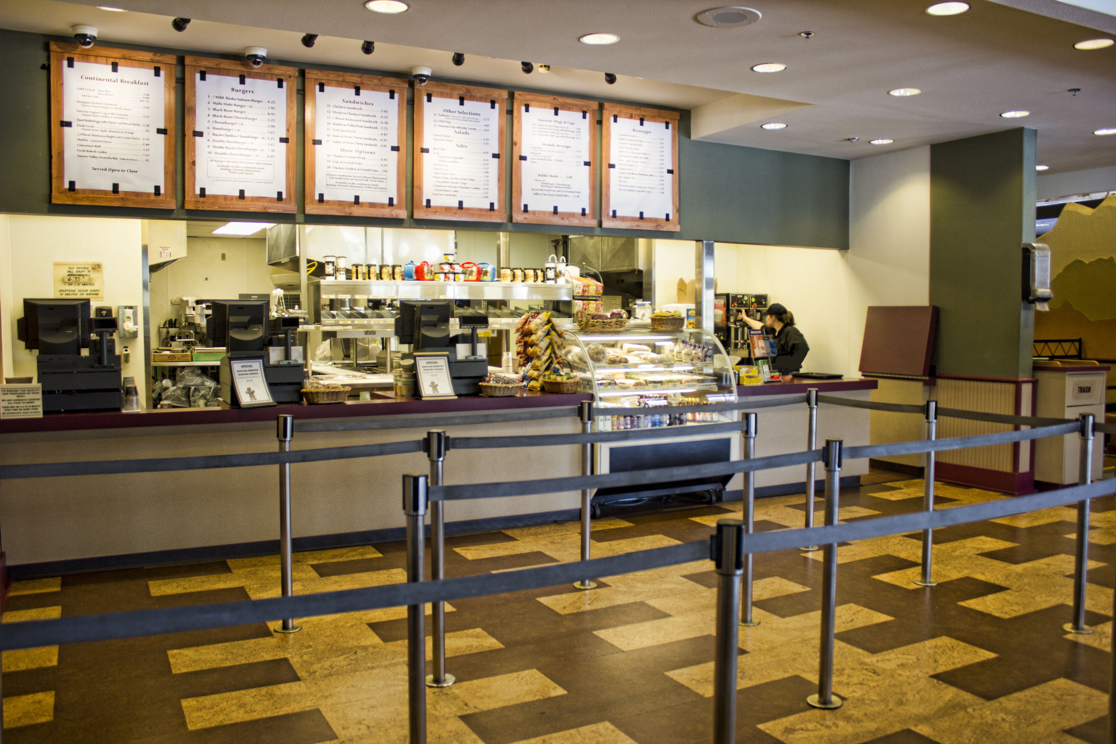 A food counter with menu boards, a coffee machine, and a display case with food items.