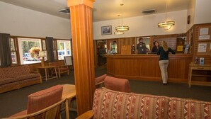 Un hall d’entrée avec un comptoir de réception, des meubles en bois et de grandes fenêtres.