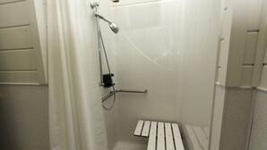 Un espace douche équipé d’un banc, d’un pommeau de douche à main et d’un panneau de commande fixé au mur.