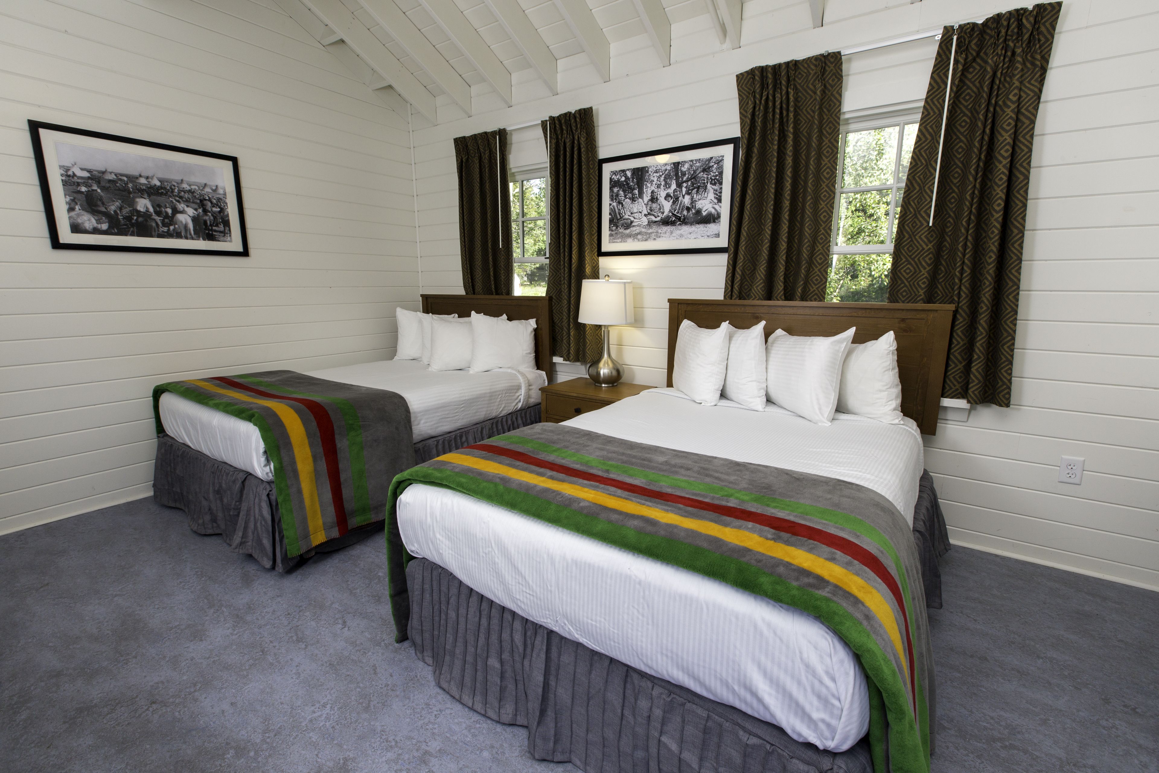 A room with two beds, a lamp, and two framed pictures on the wall.