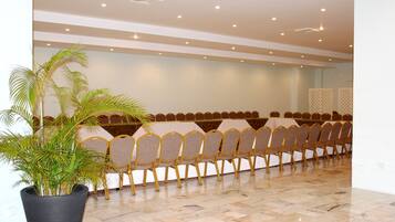 A conference room with rows of chairs, a large potted plant, and a tiled floor.