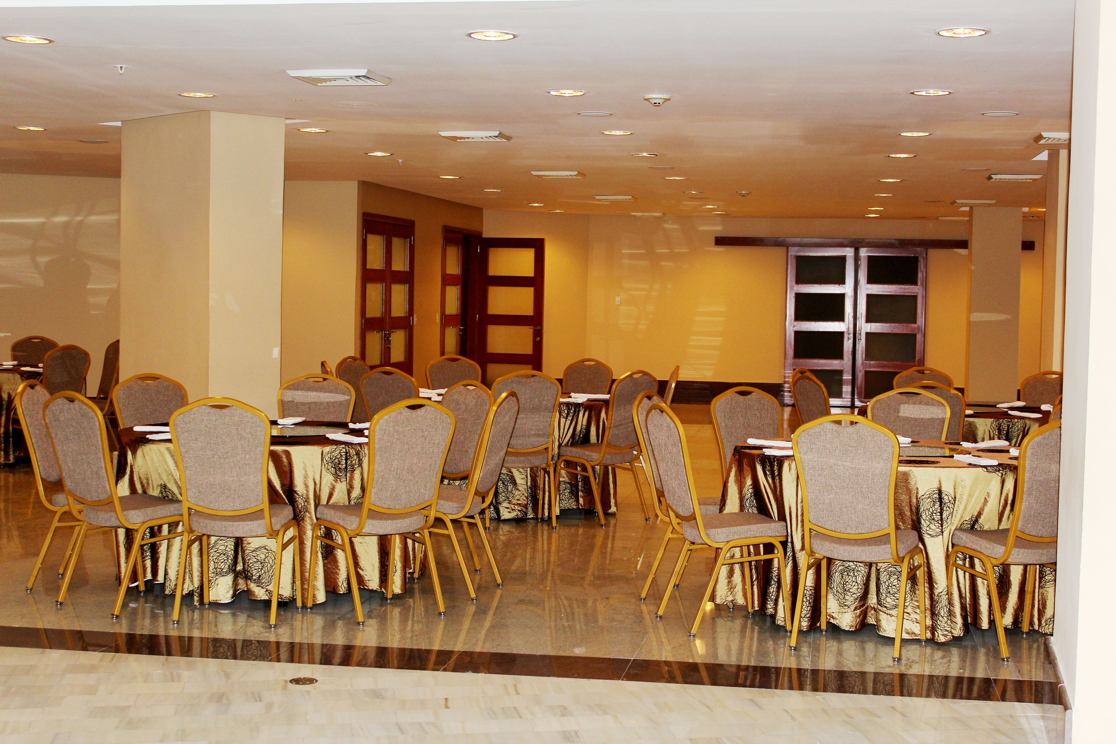 A conference room with round tables and chairs, equipped with projectors and screens.