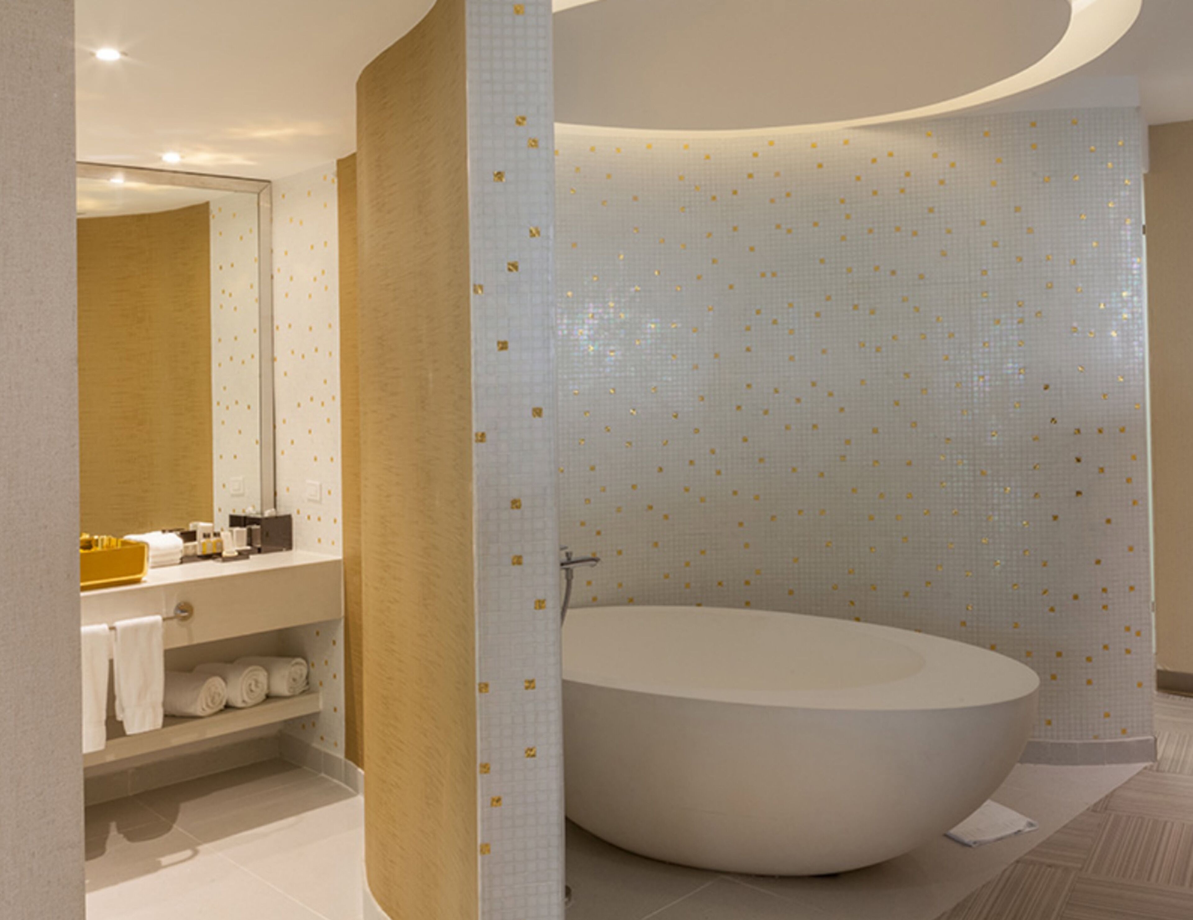 Ein modernes Badezimmer mit freistehender Badewanne, einem Waschtisch mit Spiegel und einem Handtuchhalter.