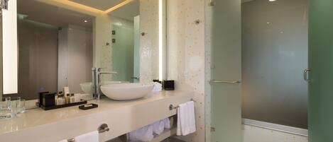 Un baño moderno con un lavamanos grande, espejo y cabina de ducha de vidrio.