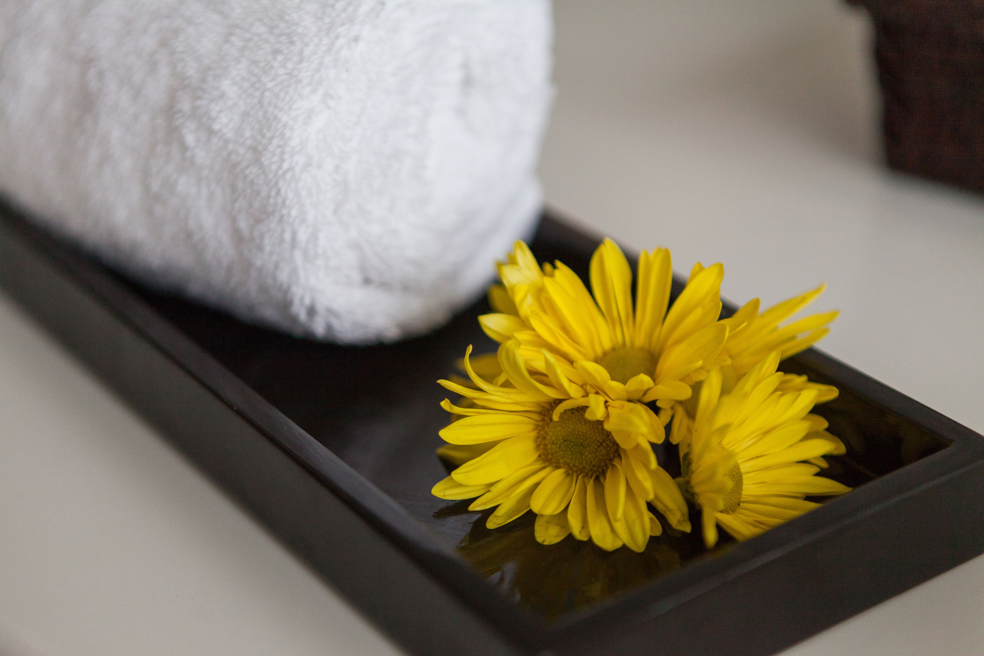 A white towel and a tray with yellow flowers.