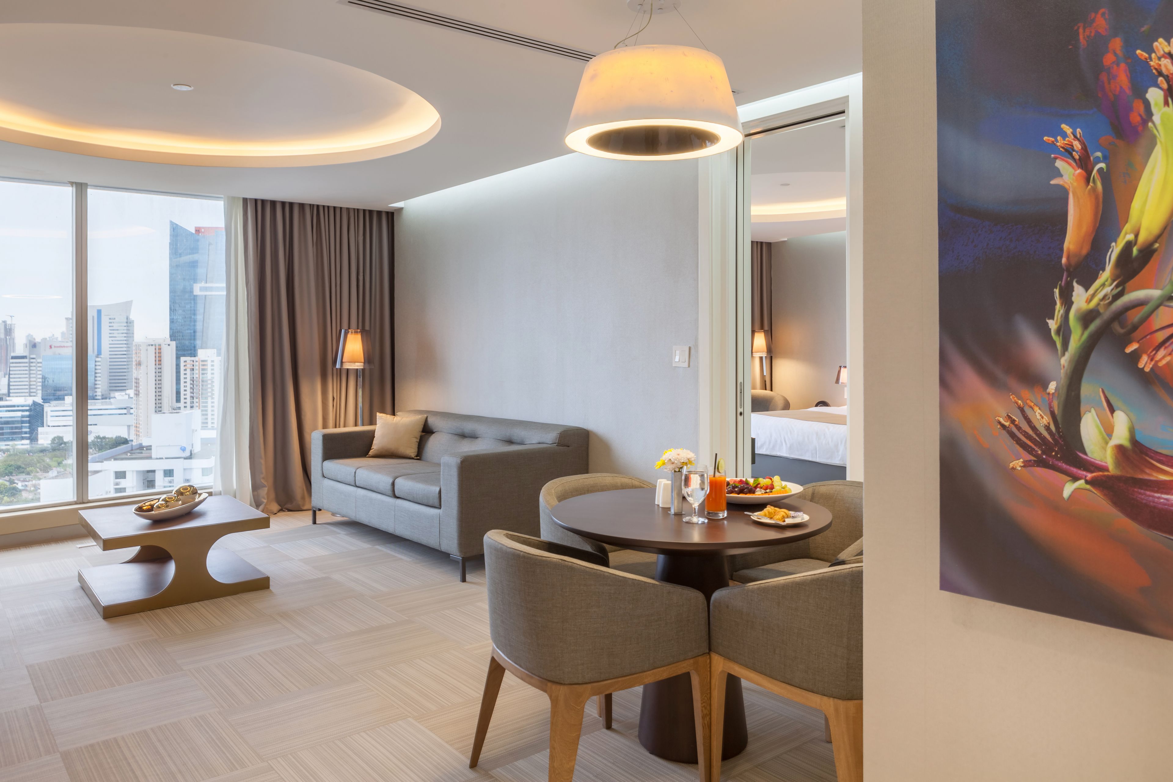 Habitación de hotel moderna con vistas a la ciudad, un área de comedor y un cuadro grande en la pared.