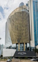 Un hotel moderno con fachada de vidrio curvo, una entrada destacada y un letrero que dice "HOTEL LAS AMÉRICAS GOLDEN TOWER PANAMÁ".